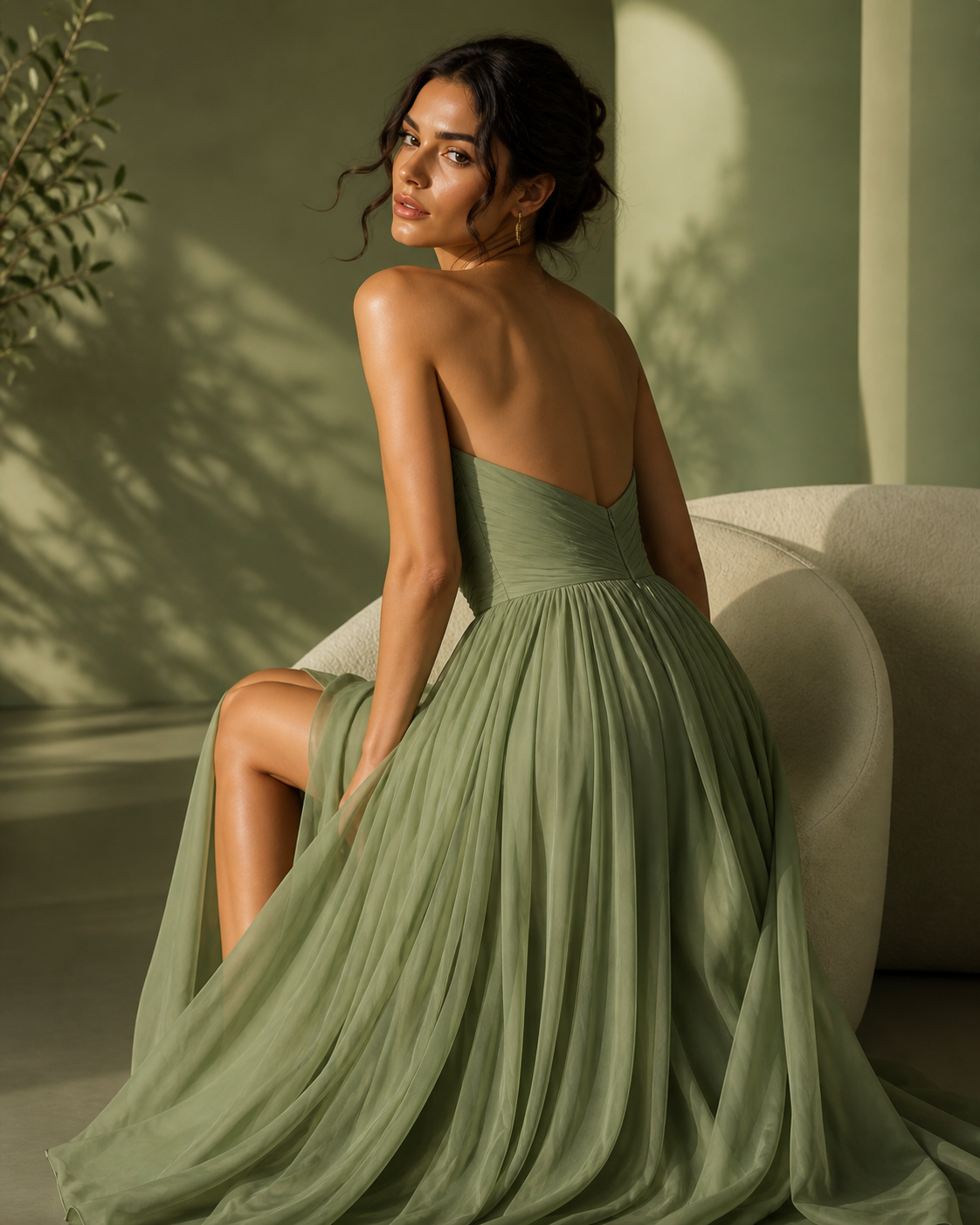 Woman in a green dress sitting on a couch with a neutral background